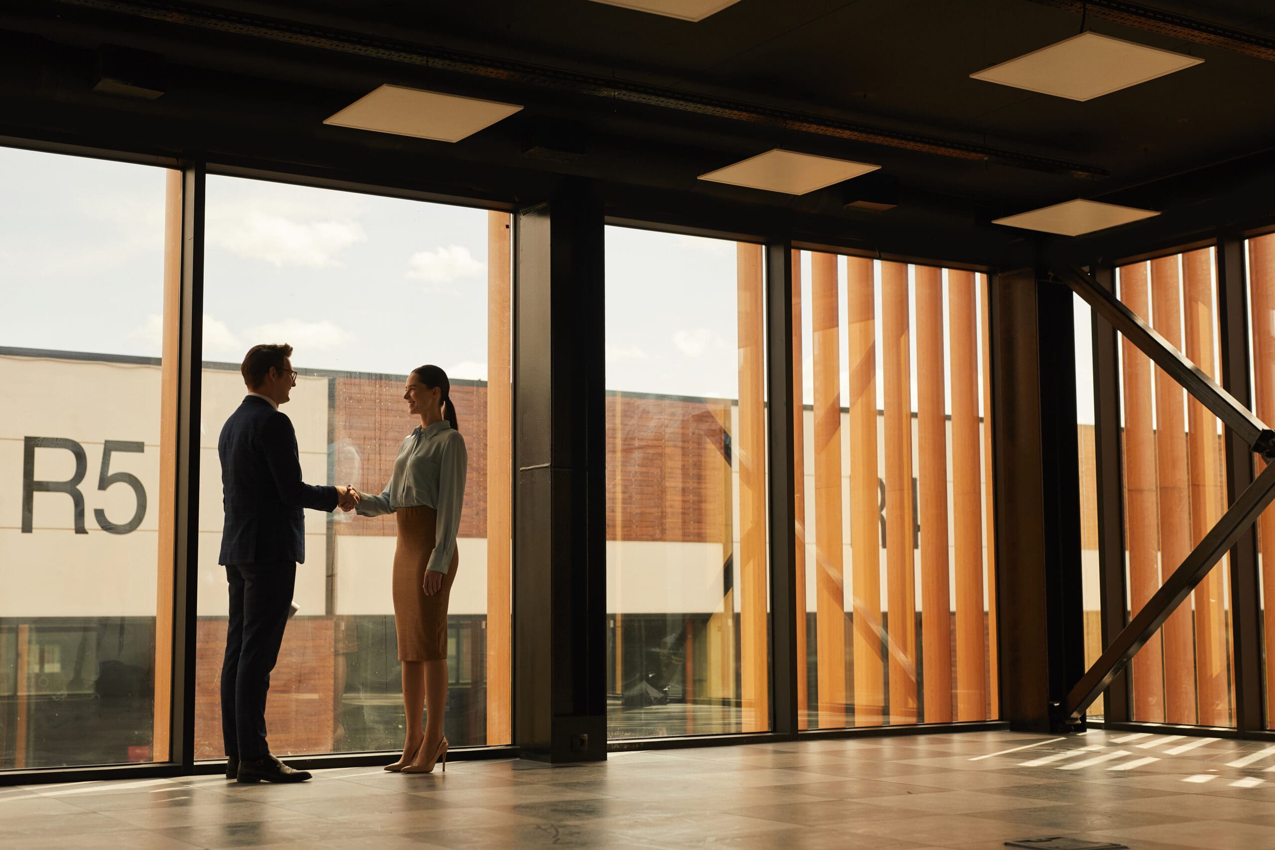 A man and woman shaking hands in a building